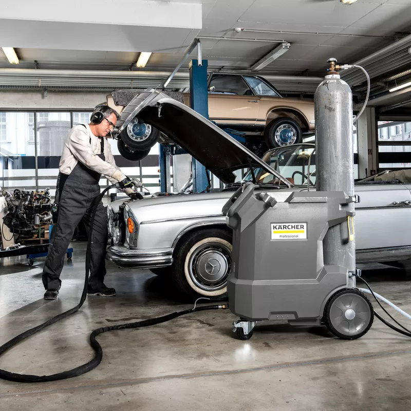 homme nettoyant un moteur dans un garage
